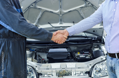 Car service. Mechanic and customer shaking hands. Excellent cooperation between car mechanic and customer.