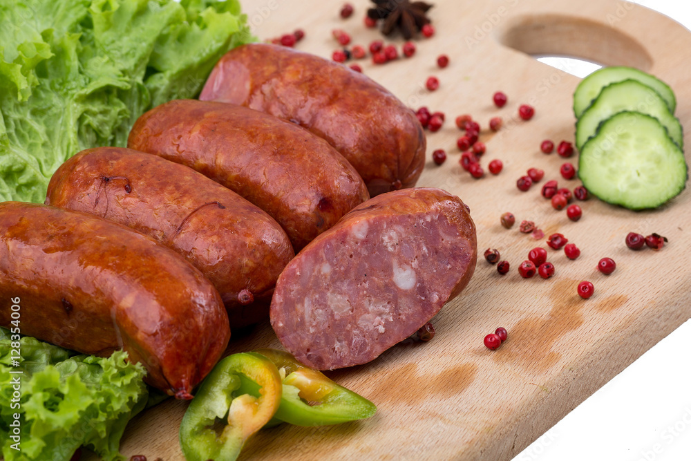 Smoked sausages on a kitchen wooden board on white background