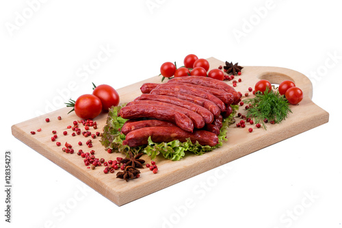 Smoked sausages on a kitchen wooden board on white background