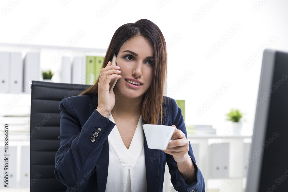 Interested brown haired businesswoman with a smartphone and a cu Interested brown haired businesswoman with a smartphone and a cu