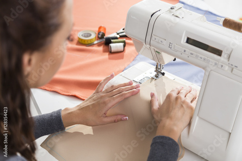 Close up of beautiful woman's hands using a sewing machine photo