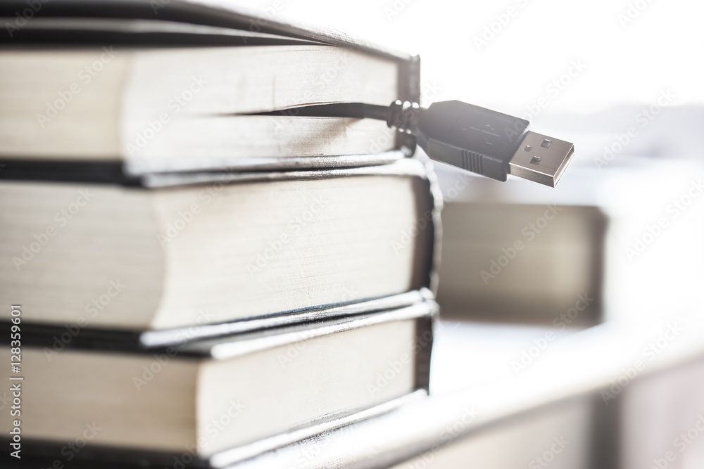 E-learning and e-book concept with usb cable coming out of a stack of books E-learning and e-book concept with usb cable coming out of a stack of books