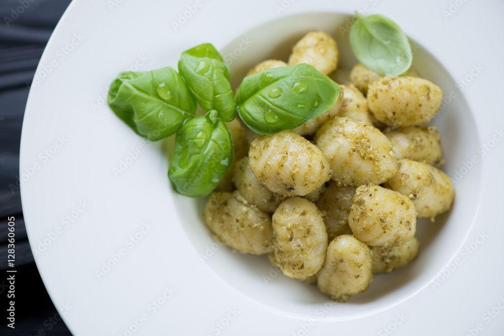 Potato gnocchi with pesto sauce and fresh basil in a white plate Potato gnocchi with pesto sauce and fresh basil in a white plate