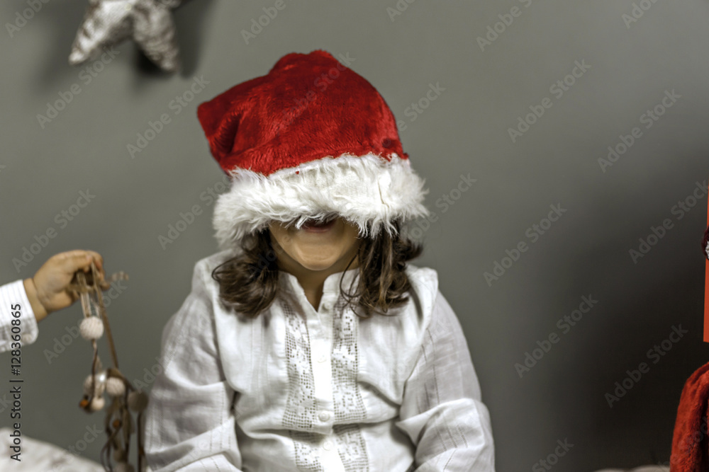 Smiley girl with Santa hat covering her face. Peekaboo. Christma Smiley girl with Santa hat covering her face. Peekaboo. Christma