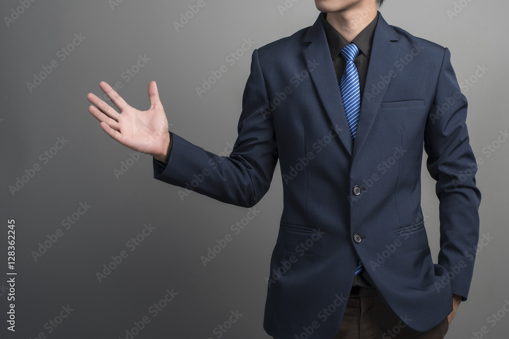 Close up of businessman in blue suit holding something on gray b Close up of businessman in blue suit holding something on gray b