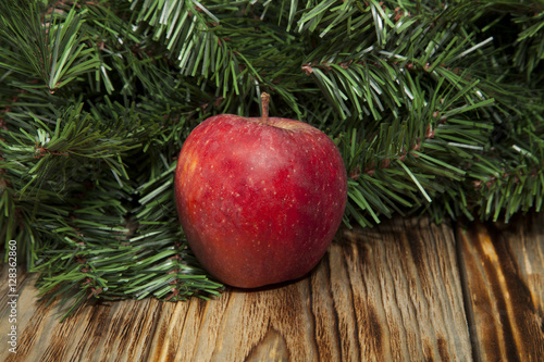 Red apple and spruce on a wooden background