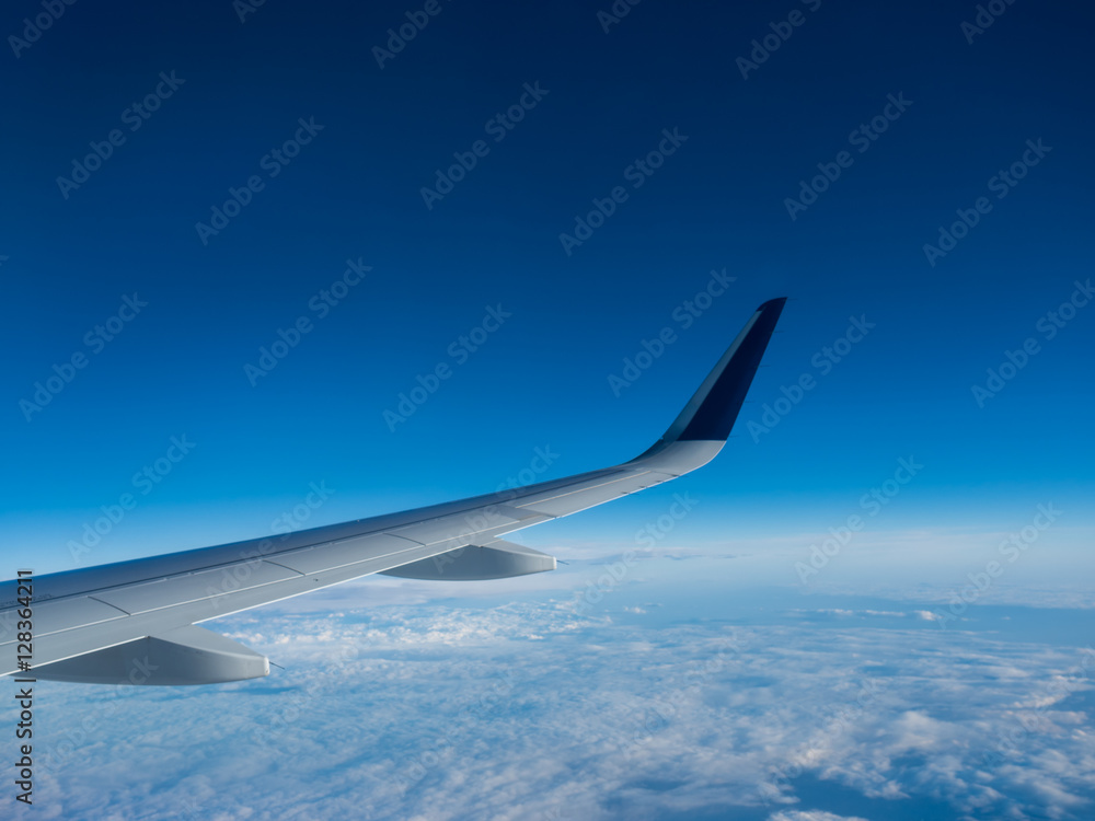 Wing of an airplane flying above the clouds on a clear sunny day Wing of an airplane flying above the clouds on a clear sunny day
