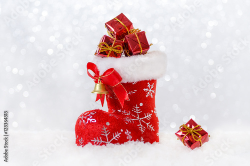 christmas stocking with gifts, santa's boot in snow, bokeh and snowflackes