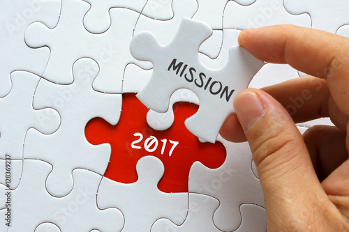 Hand holding piece of jigsaw puzzle with word MISSION 2017