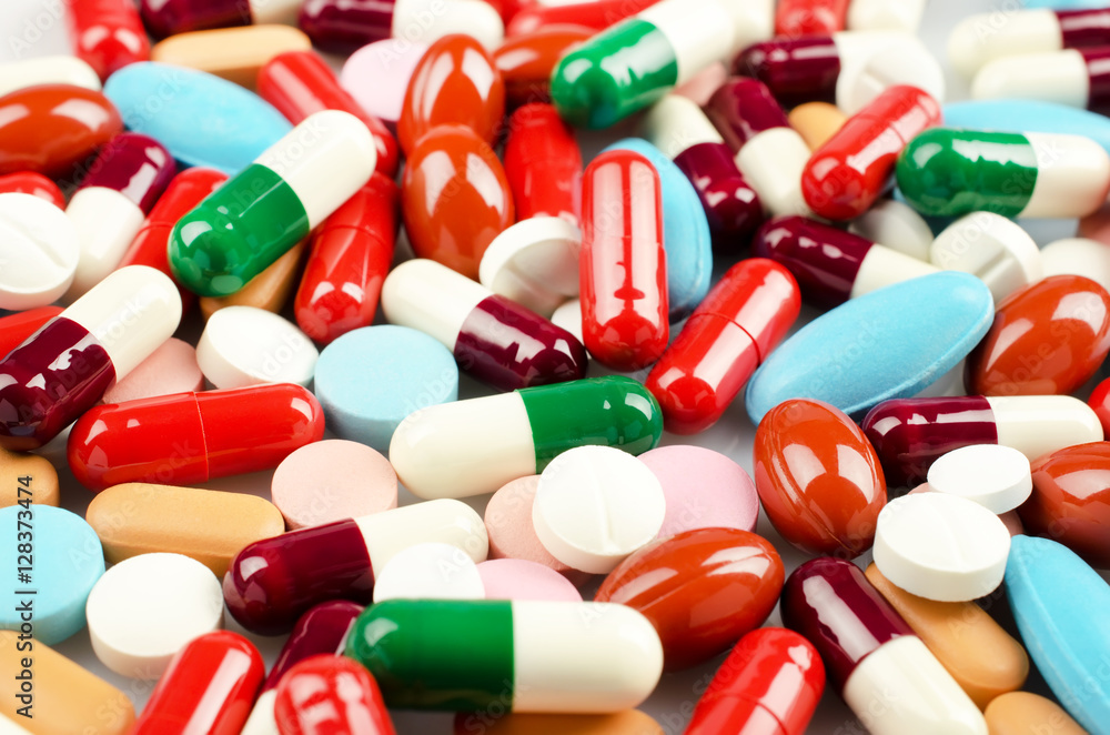 Medical theme. Multicolored Pills and Capsules on the White Surface. Closeup Medical theme. Multicolored Pills and Capsules on the White Surface. Closeup