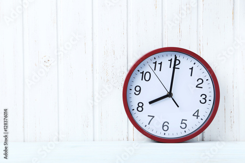 Red round clock on a wall paneling background
