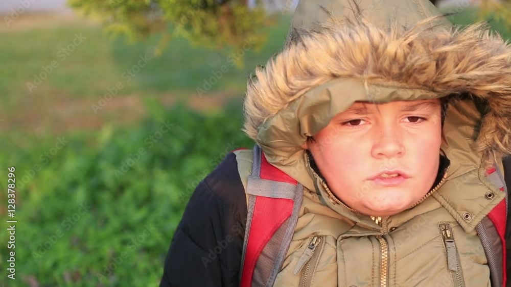 Portrait of a ill with flu sneezing young boy sitting in winter, try to warm up and blowing nose at the outdoor Portrait of a ill with flu sneezing young boy sitting in winter, try to warm up and blowing nose at the outdoor