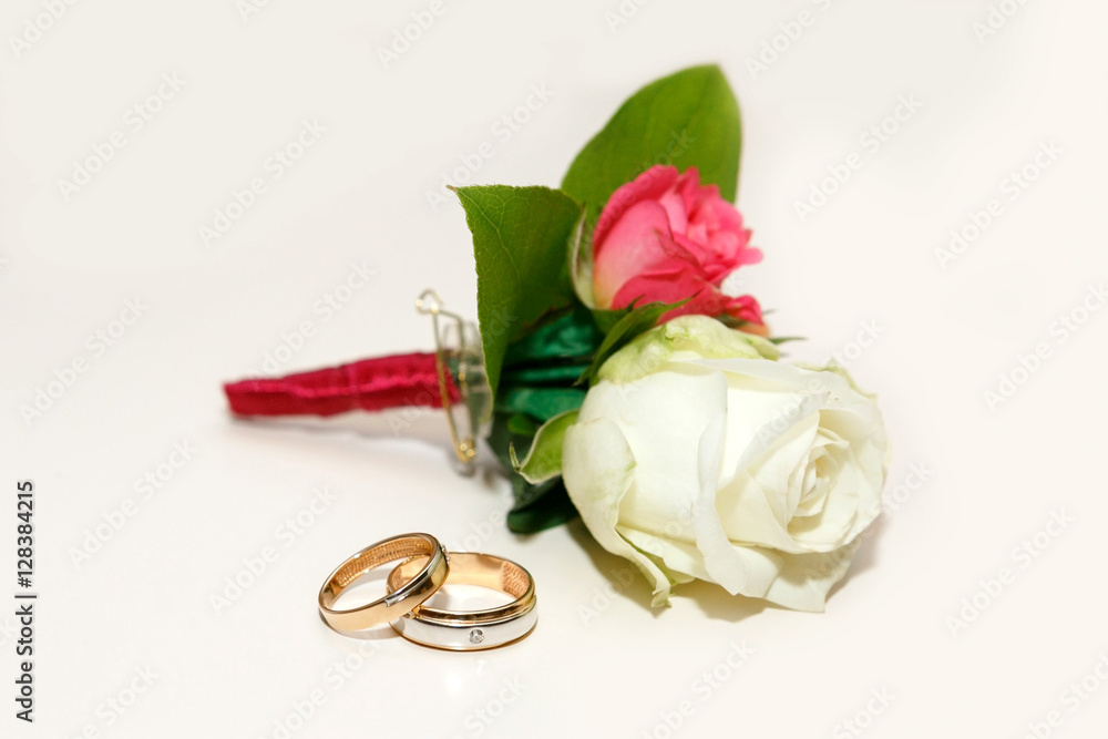 beautiful groom's boutonniere of white and red roses and wedding rings on a white table beautiful groom's boutonniere of white and red roses and wedding rings on a white table