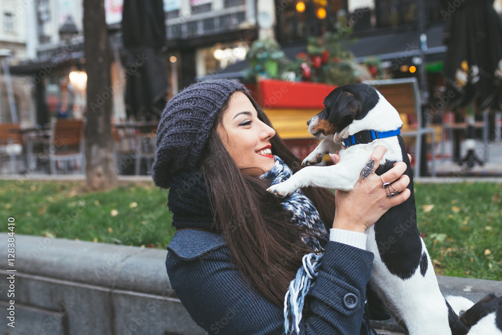 Fototapeta premium Beautiful young brunette woman enjoying city street outdoor together with her gorgeous Jack Russell terrier.
