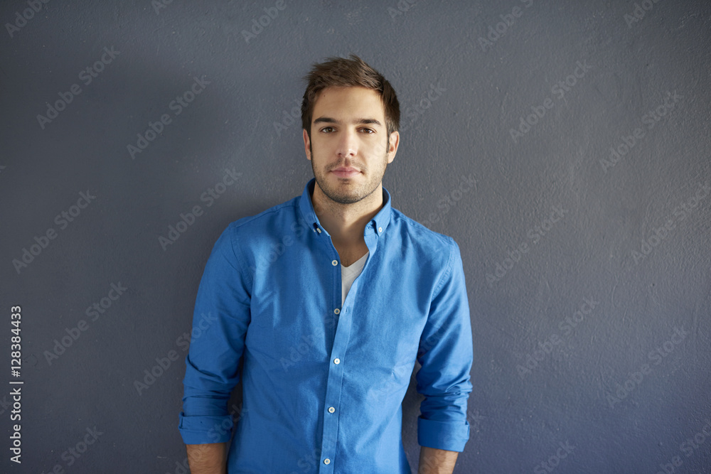 Young man portrait with copy space. Shot of a handsome man relaxing in front of a grey wall while looking at camera and smiling. Young man portrait with copy space. Shot of a handsome man relaxing in front of a grey wall while looking at camera and smiling.