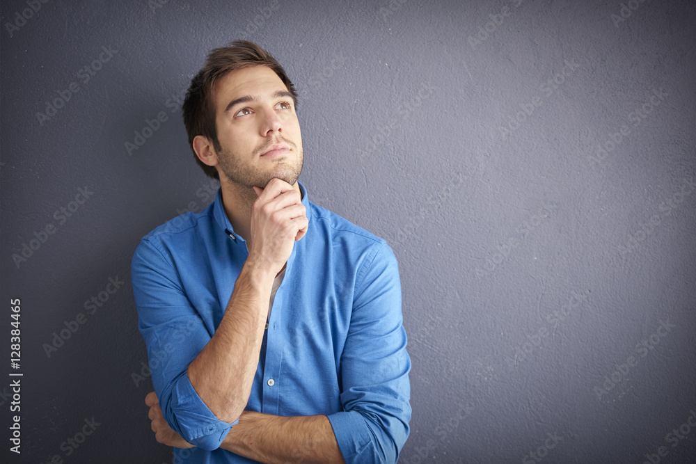 Young man portrait with copy space. Shot of a handsome man relaxing in front of a grey wall while looking at camera and smiling. Young man portrait with copy space. Shot of a handsome man relaxing in front of a grey wall while looking at camera and smiling.