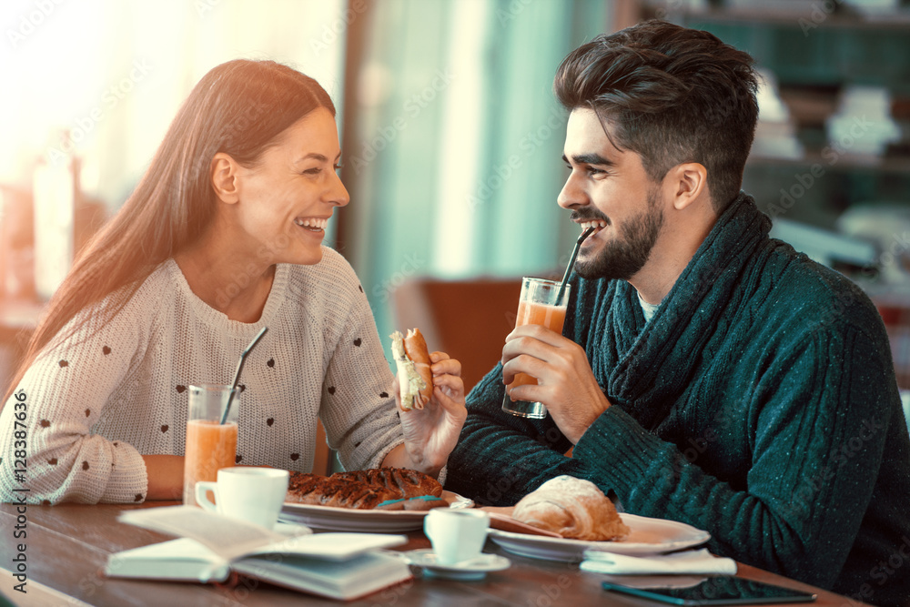 Happy young couple having breakfast in cafe