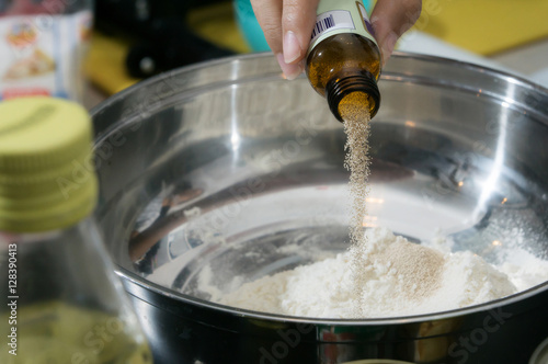 pouring some yeast in to the stainleass blow mixing with flour preparation step to cooking some food that by flour