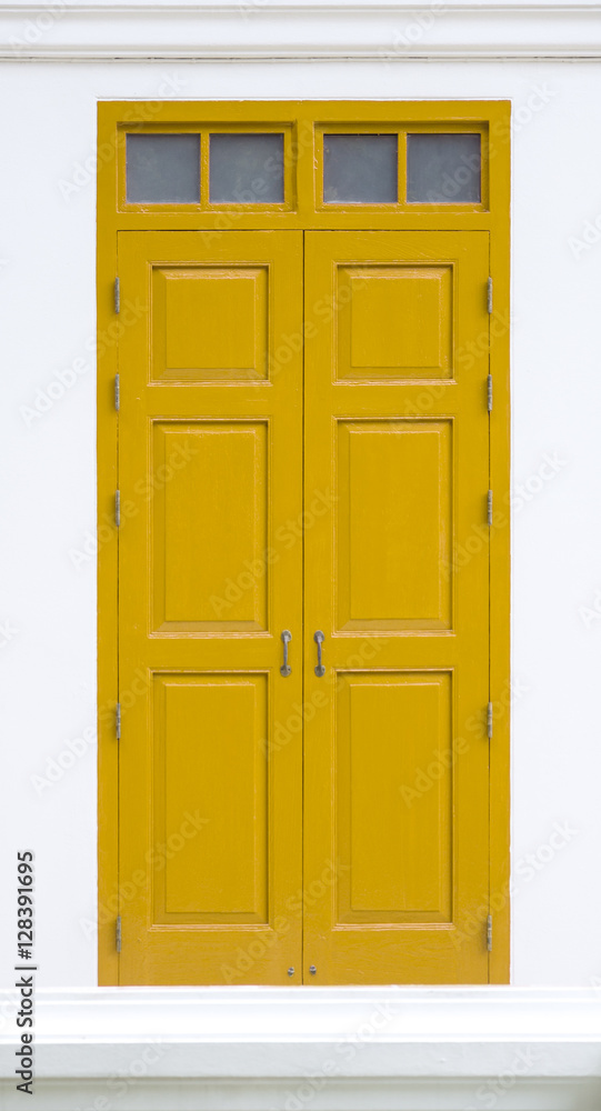 traditional yellow door wooden of an old on white wall,in Thailand