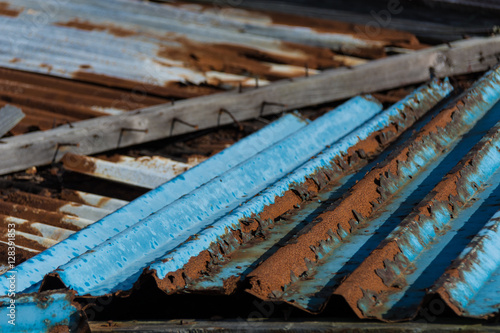 Blue and galvanised corrugated metal panels discarded and rusty