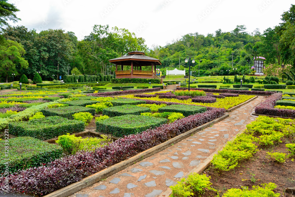 Fototapeta premium Country cottage garden path. Thai style pavilion is located in the middle with tree background.
