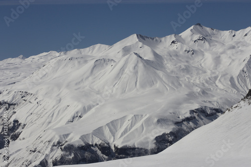 Mountain peaks in the snow. View of the mountain on the horizon. © Elena