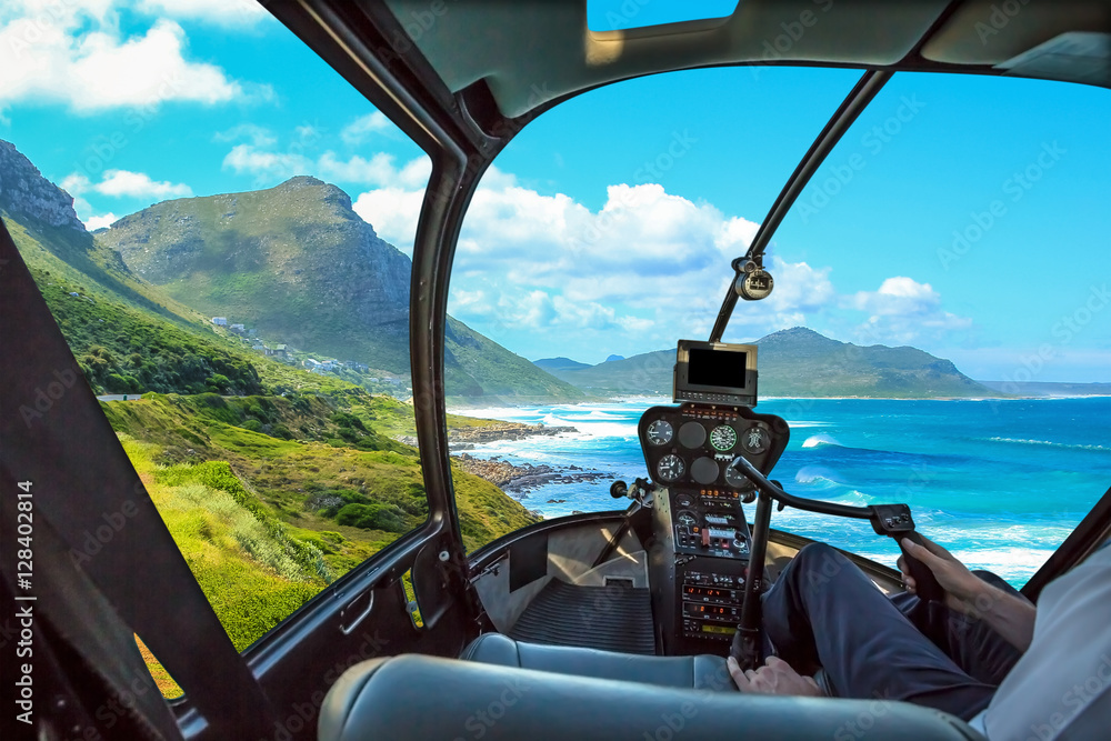 Naklejka premium Helicopter cockpit flies in Misty Cliffs, Cape Peninsula in South Africa, with pilot arm and control board inside the cabin.