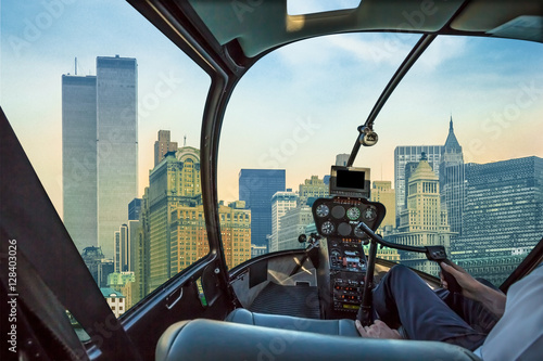 Helicopter cockpit flies in New York City with World Trade Center and Twin Towers, Manhattan, United States, with pilot arm and control board inside the cabin.