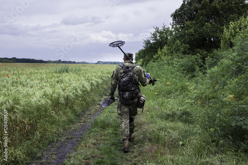 Man waking with metal detector thru the fields