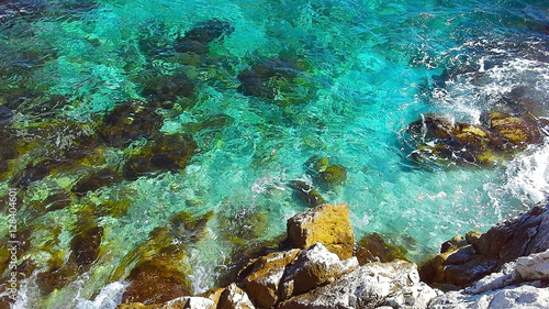 Transparent turquoise water near rocky coast, ripple on surface