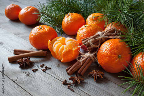  Tangerines with cinnamon, anise and fir branches on a wooden table. Christmas background card with fruits.