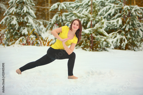 beautiful woman doing yoga outdoors in the snow