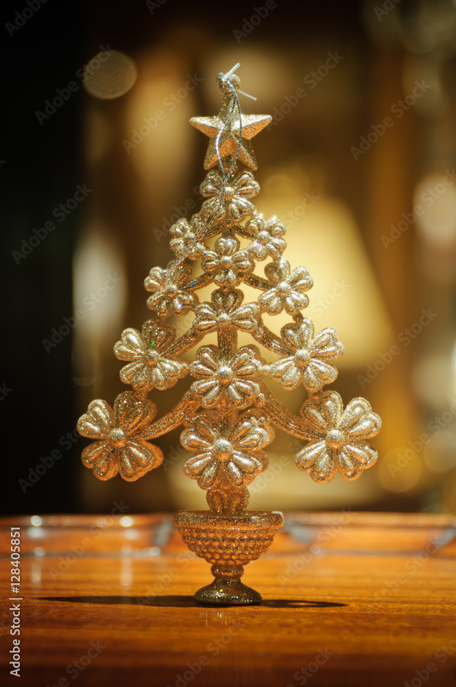 Fototapeta premium Ornament - Christmas Tree / Sparkling christmas tree ornament stands on polished wood table top. Background booked.