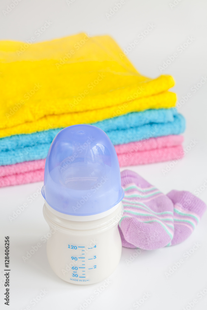 baby bottle with milk and towel on white background
