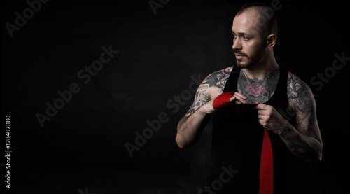 Hairless man with pumped up body with tatoo prepairing for a fighting. Man look to the copy space for advertising sport goods. Strong guy.