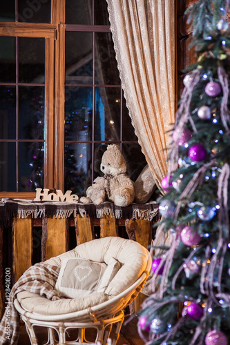 Rustic wooden living room with big windows, decorated lilac Christmas tree and cozy papasan chair photo