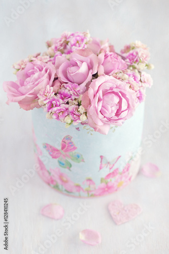 Lovely bunch of flowers .Beautiful fresh roses flowers in a box decorated with a heart on a pink background with texture .