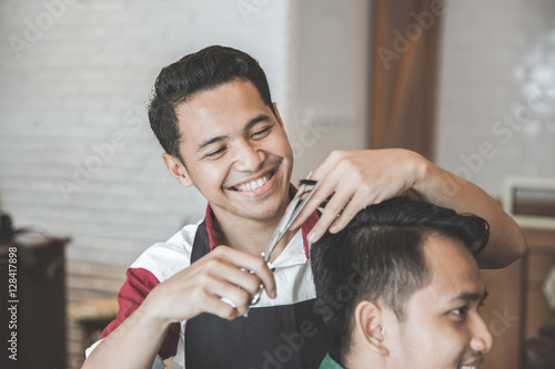 man getting haircut by hairdresser at barbershop