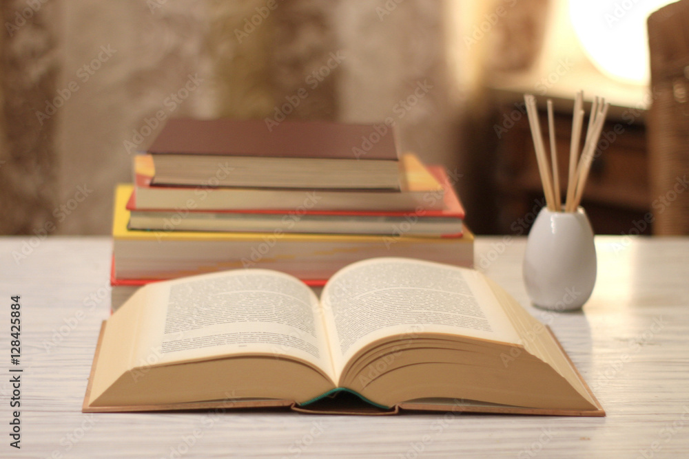 Fototapeta premium aufgeschlagenes Buch und Bücherstapel auf einem Tisch