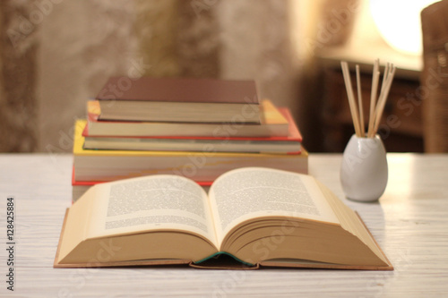 aufgeschlagenes Buch und Bücherstapel  auf einem Tisch