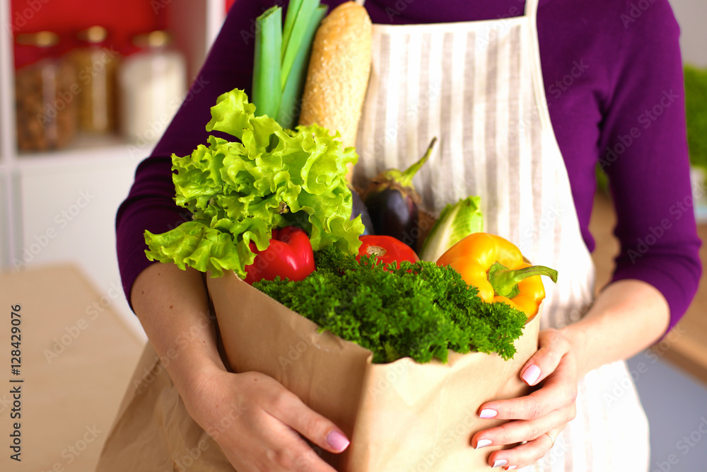 Healthy positive happy woman holding a paper shopping bag full of fruit and vegetables