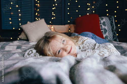 cute little girl in a sweater on the bed on a winter day