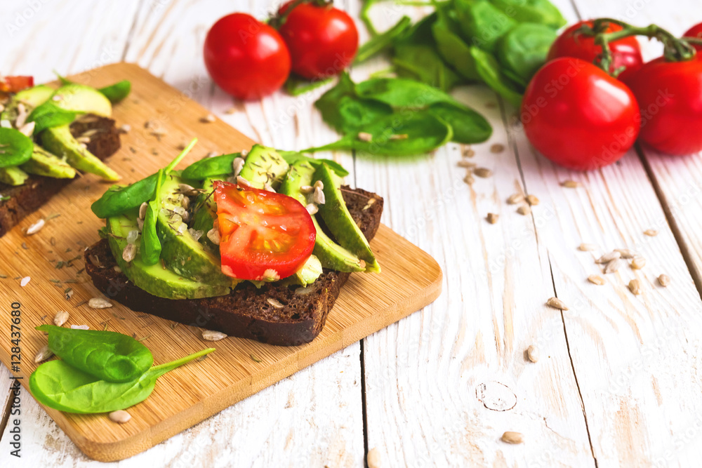 Toast with sliced avocado, tomatoes, spinach and spices