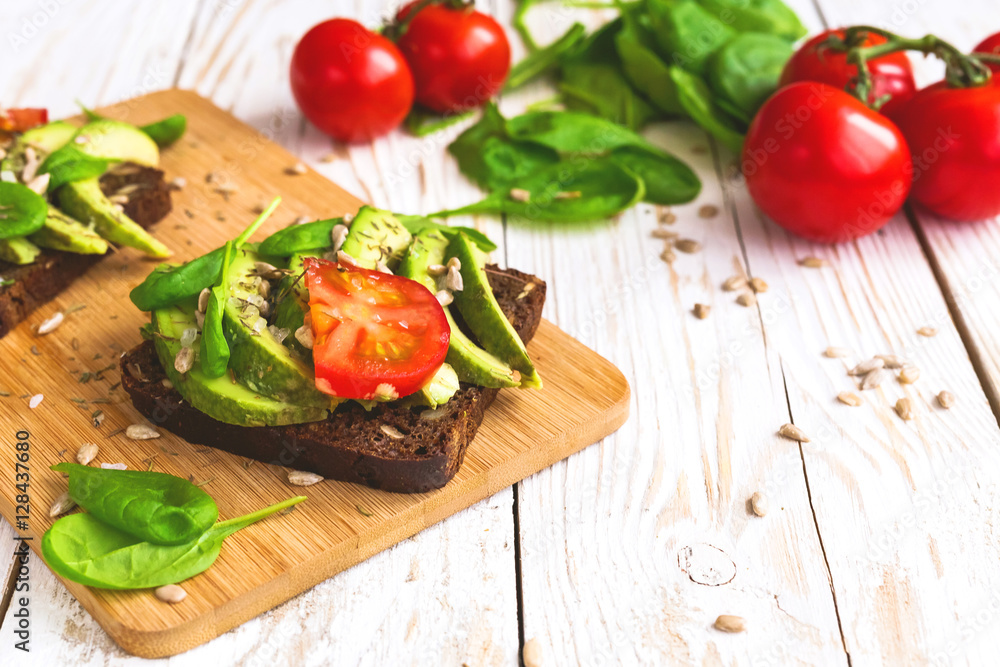 Toast with sliced avocado, tomatoes, spinach and spices Toast with sliced avocado, tomatoes, spinach and spices