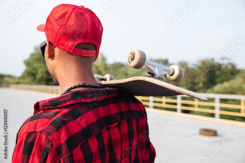 Young dark skinned guy holding skateboard