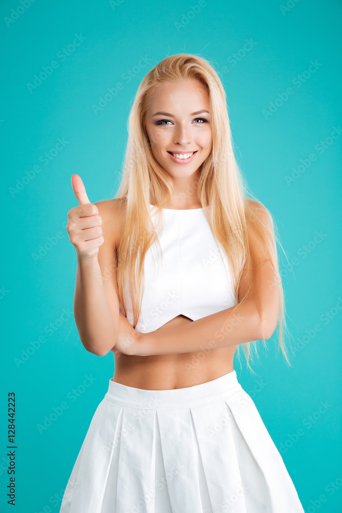 Smiling young woman standing and showing thumb up Smiling young woman standing and showing thumb up