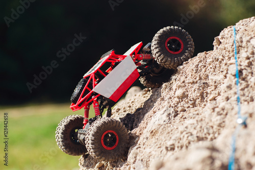 Side view on crawler rising on rock hill. Small buggy car overcoming mountain rough rock. Going to win, leisure, competition, extreme concept photo