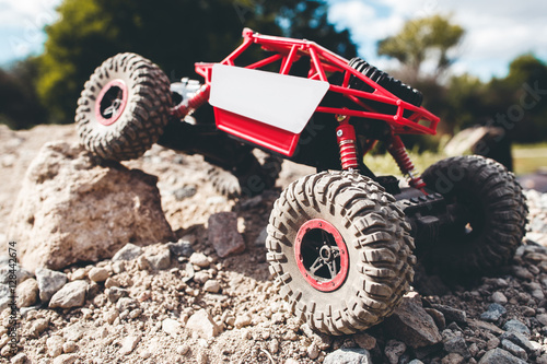 Toy crawler overcoming rock close-up. Rc offroad car riding rocky landscape. Buggy, rally, leisure, entertainment concept photo