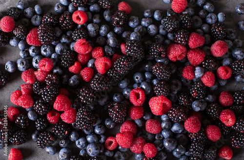 Raspberries, blackberries, blueberries a gray abstract background. Copyspace. Healthy food concept.  Colorful festive still life. Loosely laid berries in different positions