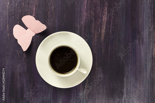 Black coffee and paper butterfly on purple background